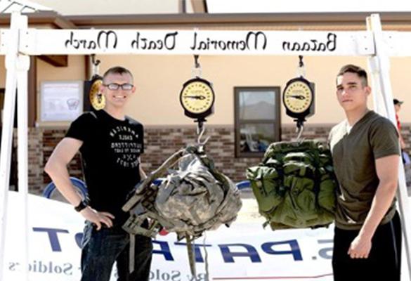 Two ROTC male students weighing their gear at the end of the Bataan Memorial Death March