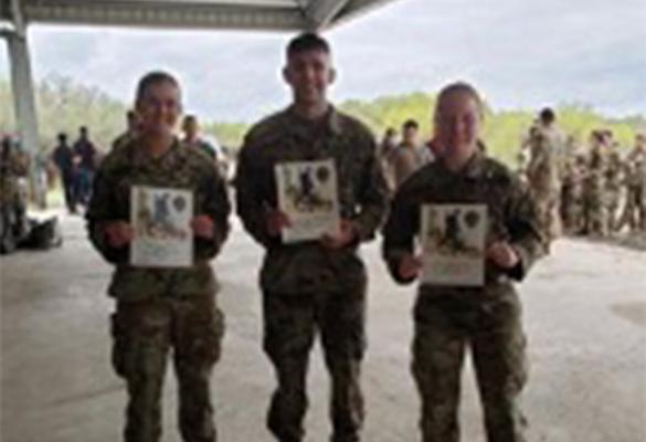 Three ROTC Students smiling showing their Norwegian Foot March Badge Certificate